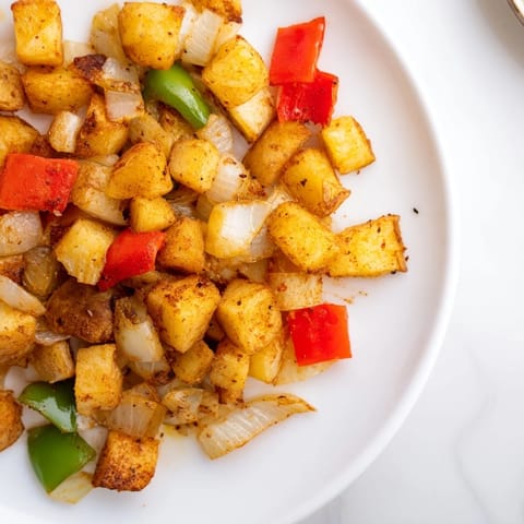 Sizzling skillet of home fries showcasing browned potatoes, onions, and bell peppers for a flavorful side.