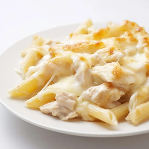 Golden-brown Chicken Alfredo Casserole fresh from the oven, bubbling with melted mozzarella and creamy sauce over penne pasta.  