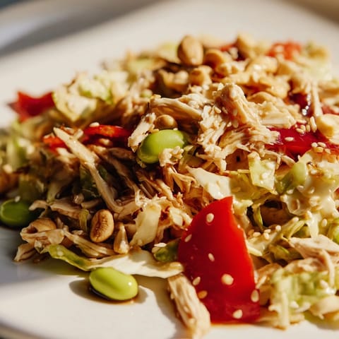 Edamame Crunch Chicken Salad in a white bowl, topped with toasted sesame seeds and cashews, ready for a light lunch.