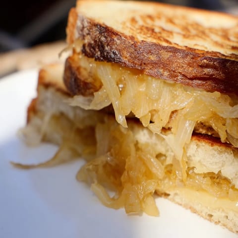 Warm, nutty Gruyère and slow-cooked onions ooze from a buttery, golden-brown sandwich, served fresh and hot.