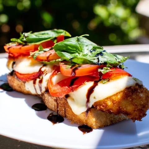 Crispy Chicken Caprese Sandwich on toasted ciabatta with melted mozzarella, ripe tomato slices, and fresh basil leaves.
