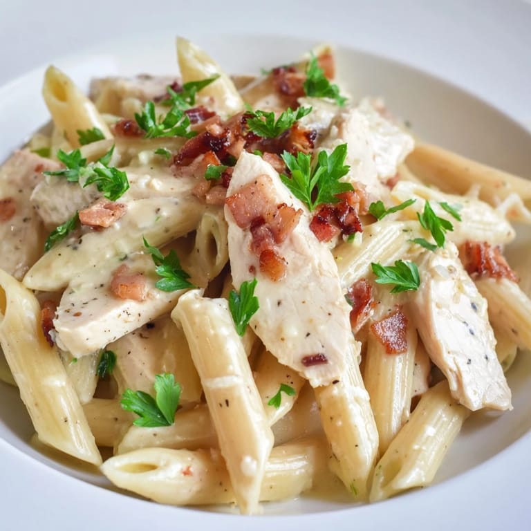 Steam rises from a bowl of Creamy Chicken Bacon Penne featuring tender chicken and smoky bacon.