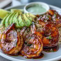 Fresh shrimp, avocado, and quinoa bowls topped with vibrant mango salsa, drizzled with zesty lime chili sauce for dinner.