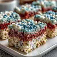 Patriotic Rice Krispies Treats with red, white, and blue layers, chewy and colorful, perfect for Fourth of July celebrations.